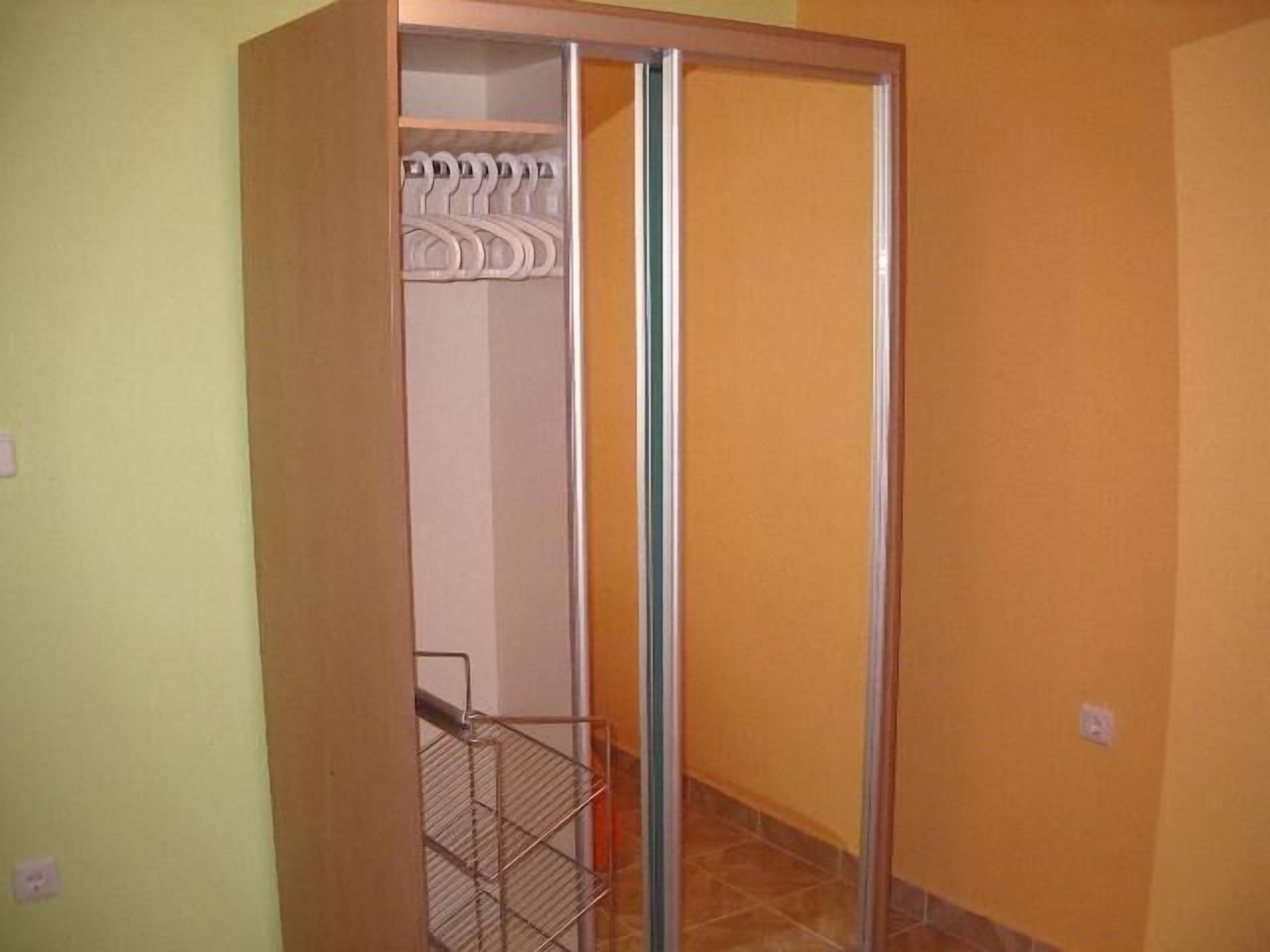 Een kamer met een schuifdeur die uitkomt op een inloopkast met kleding.