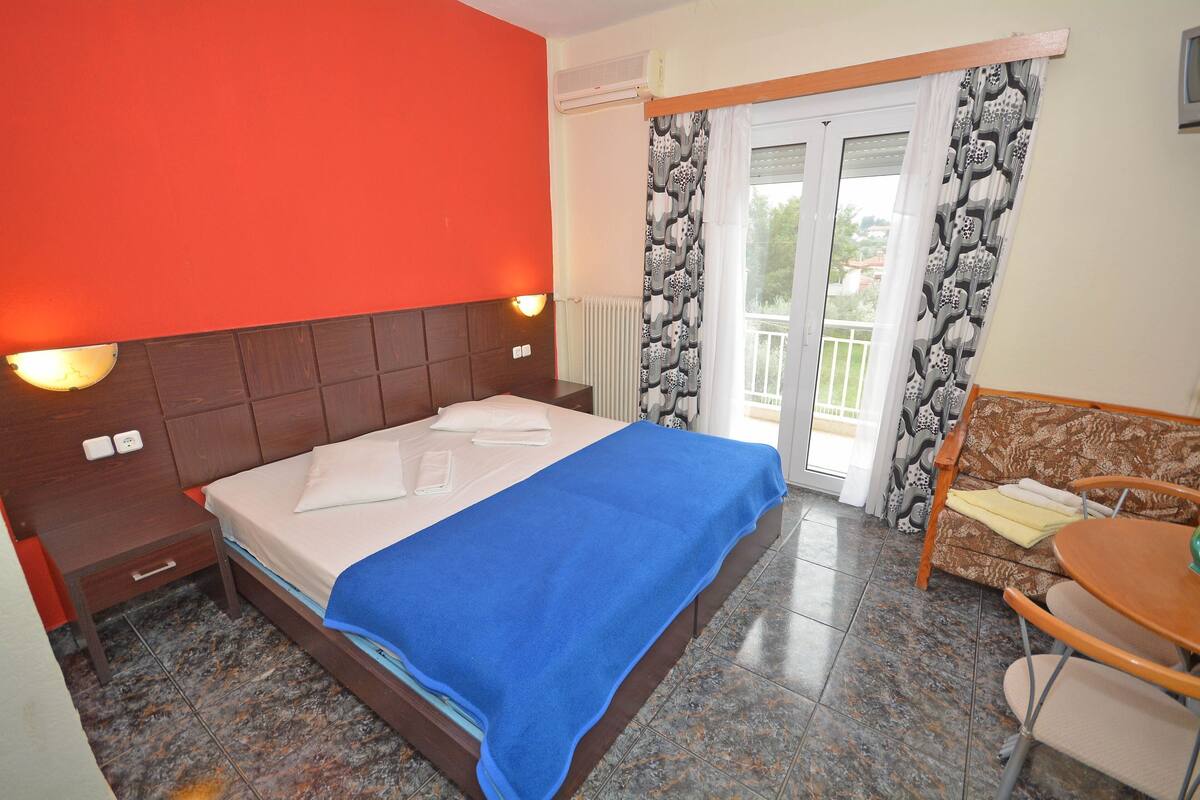 Een hotelkamer met een bed, nachtkastje, tafel en bank.
