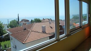 A view from a window overlooking a residential area with a tiled roof and a clear sky.