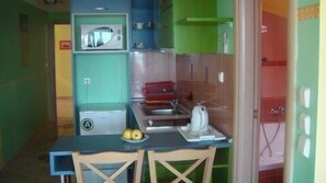 A compact kitchen with a microwave, sink, and a small dining area with a table and chairs. - Hotel Dias Apartments (Pydna-Kolindros)