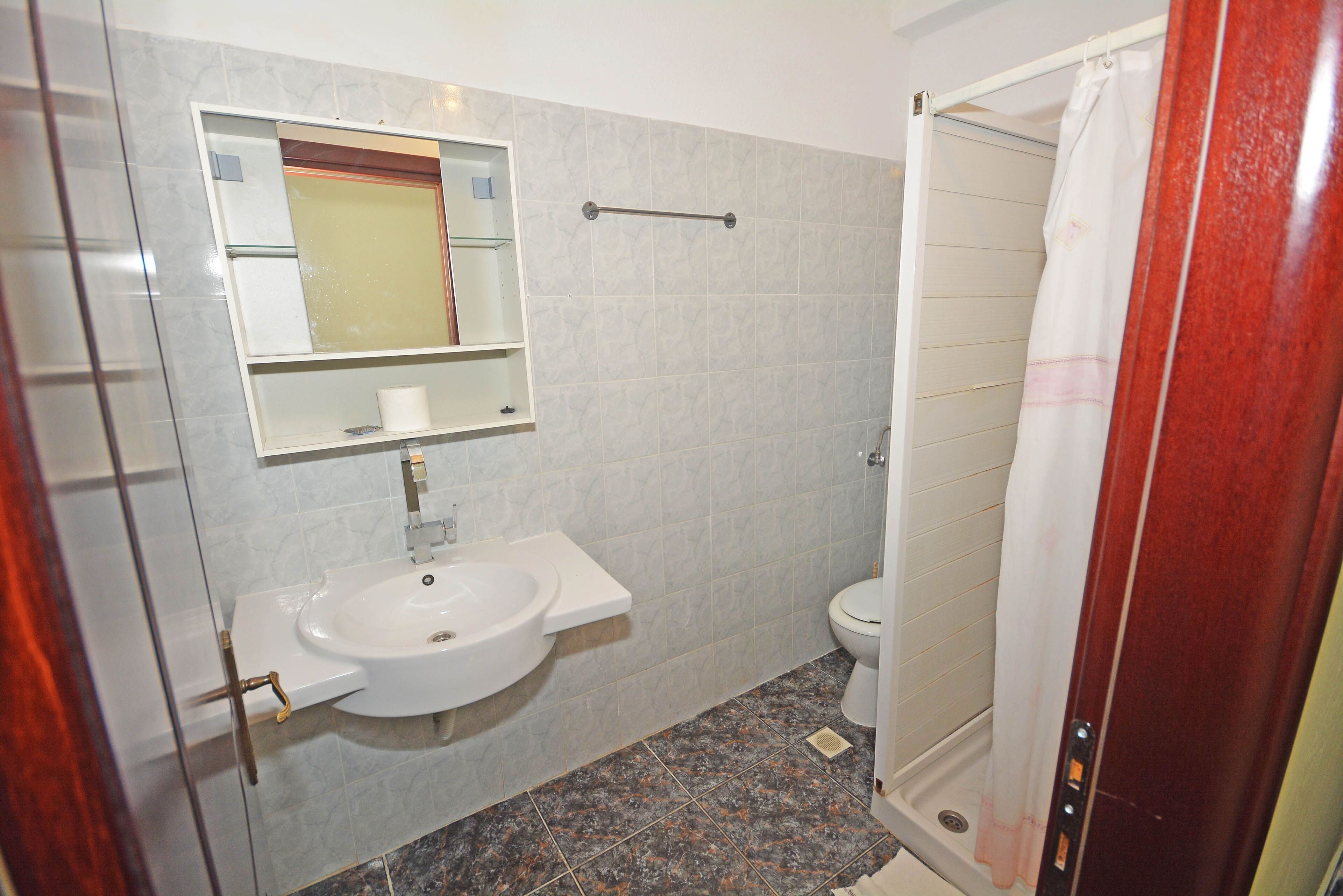 A bathroom with a white sink, mirror, and toilet.
