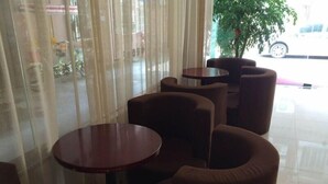 A seating area with round tables and cushioned chairs, a large window with sheer curtains, and a potted plant. - Greentree Inn Fujian Xiamen University Business Hotel (Xiamen)