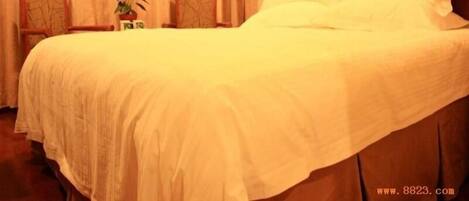 Un lit bien fait, avec du linge de lit blanc, dans une chambre d’hôtel.