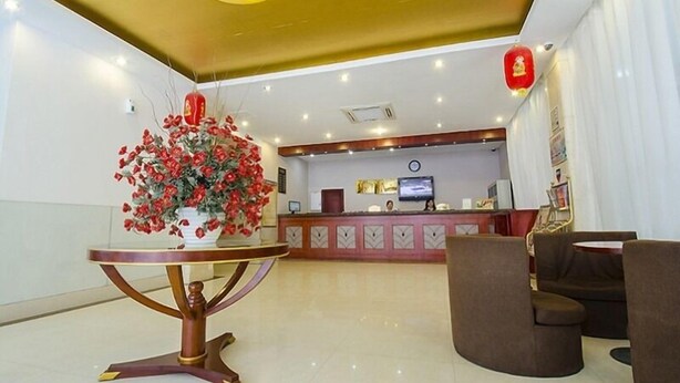 A hotel lobby with a reception desk, a large artificial red flower arrangement, a round table, and a sofa. - Greentree Inn Fujian Xiamen University Business Hotel (Xiamen)