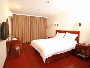Une chambre d’hôtel avec un grand lit, un bureau avec une chaise, une télévision et une fenêtre avec des rideaux.