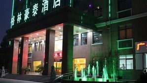 A hotel with a modern facade, illuminated signage, and a fountain in the courtyard. - GreenTree Inn Hefei XiYou Road Hotel (Hefei)