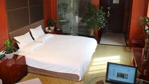A hotel room with a large bed, a desk with a computer, and two potted plants. - GreenTree Inn Hefei XiYou Road Hotel (Hefei)