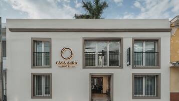Un edificio moderno con un letrero que dice 'CASA AURA HOTEL' y varias ventanas.