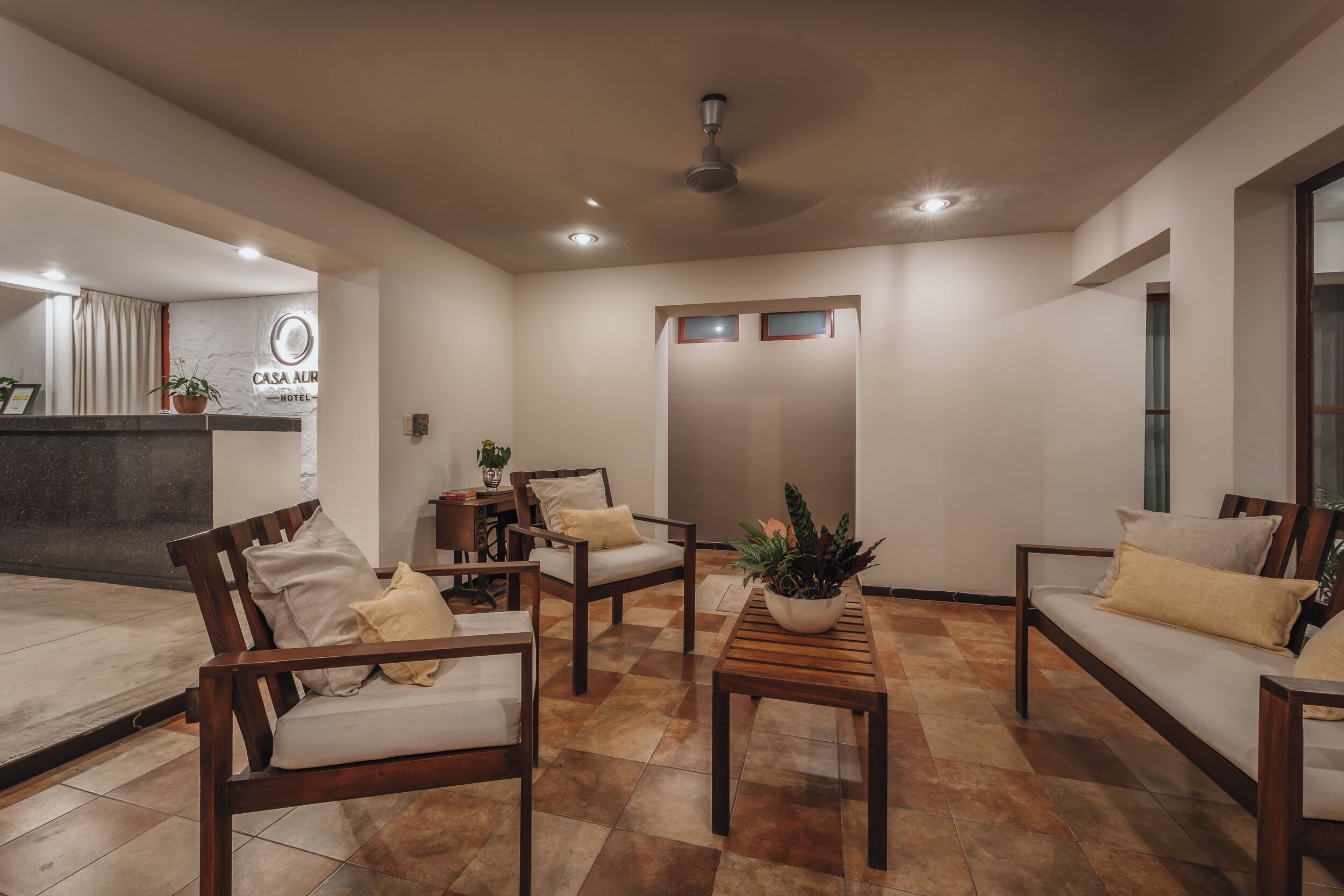 A hotel lobby with a reception desk, seating area, and a staircase.