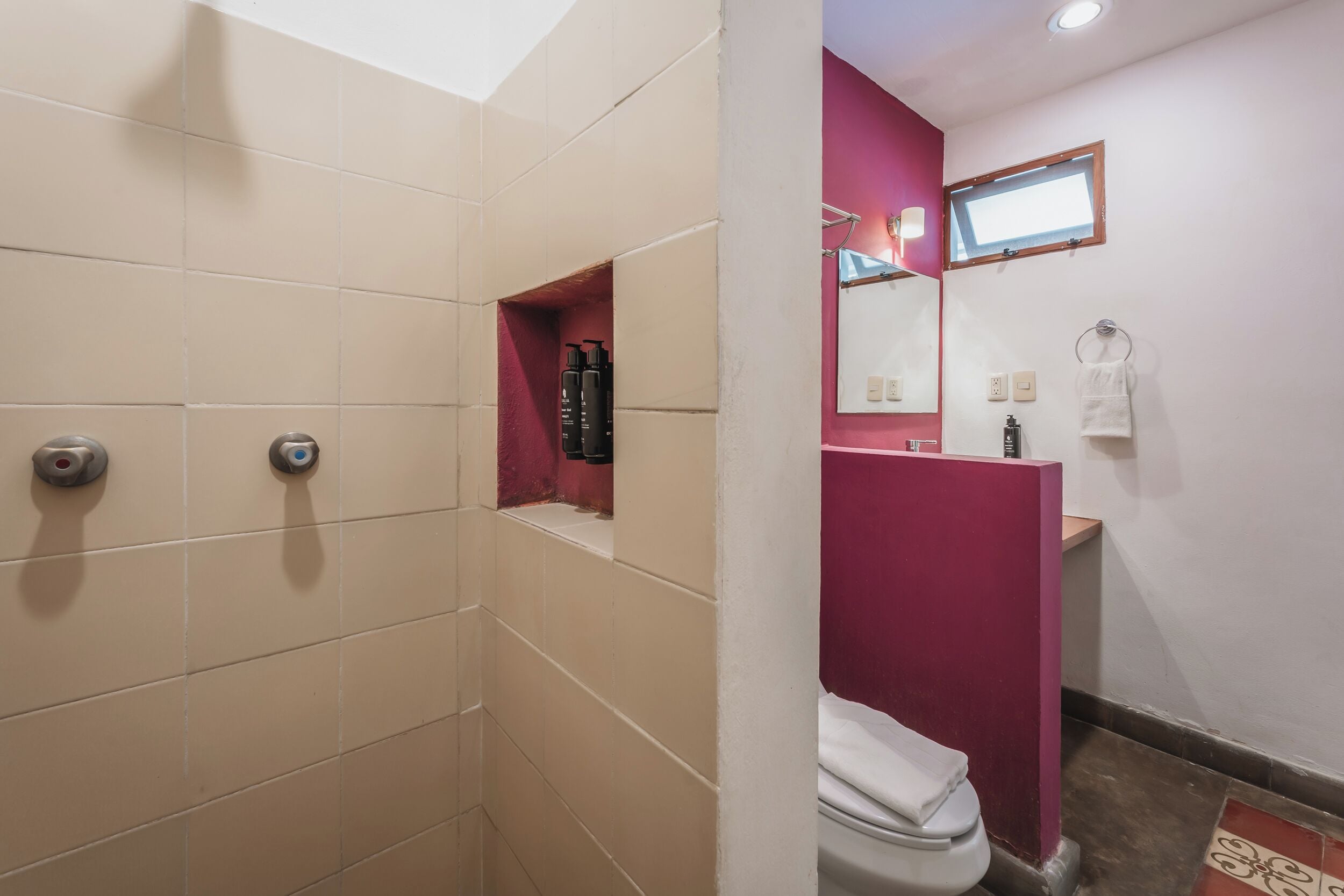 A bathroom with a shower, toilet, and a sink area.