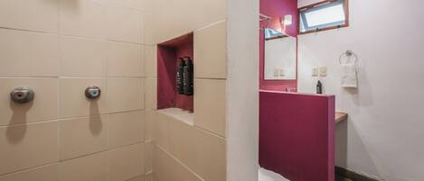 A bathroom with a shower, toilet, and a sink area.