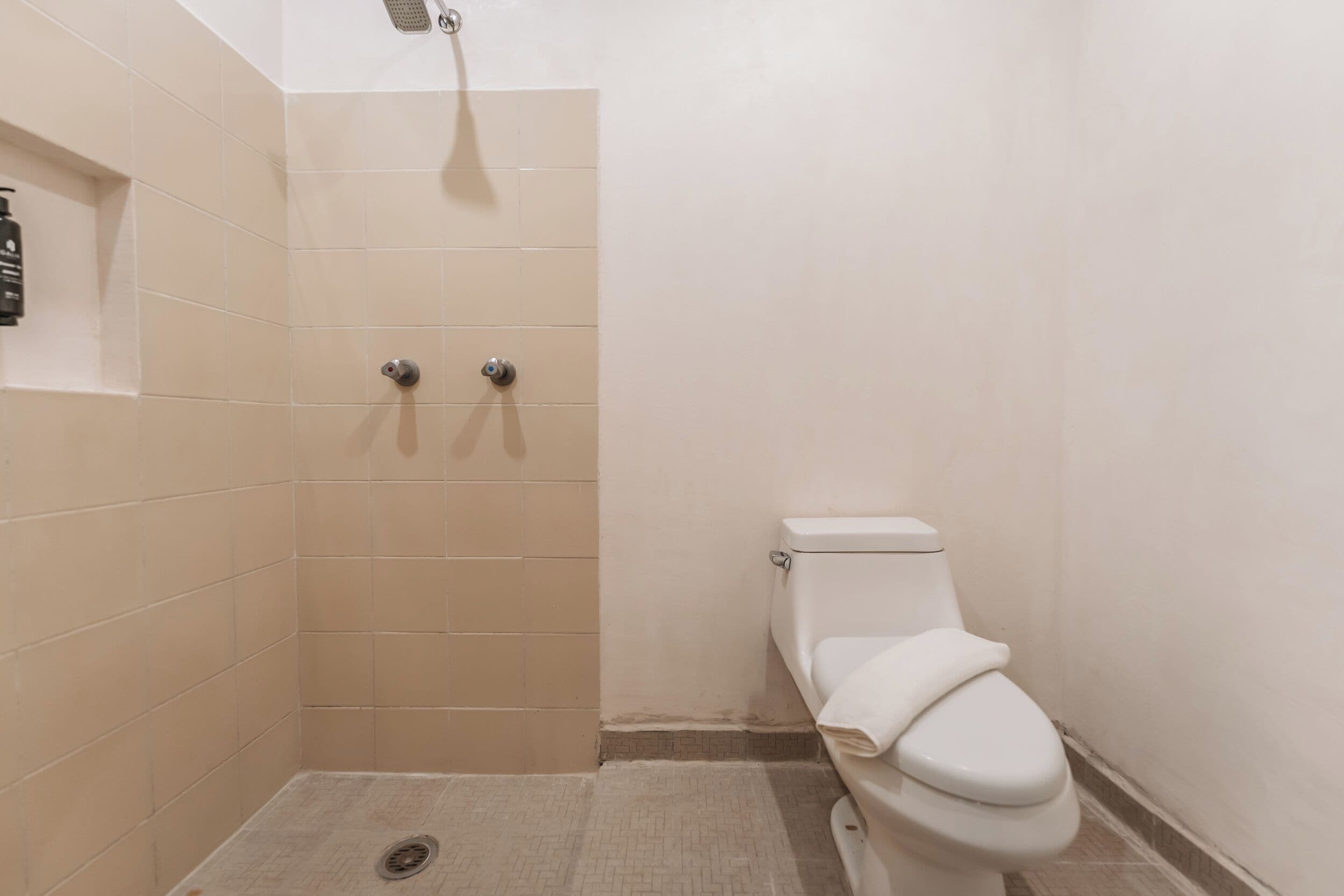Une petite cabine de douche fermée, avec des toilettes sur le côté droit.