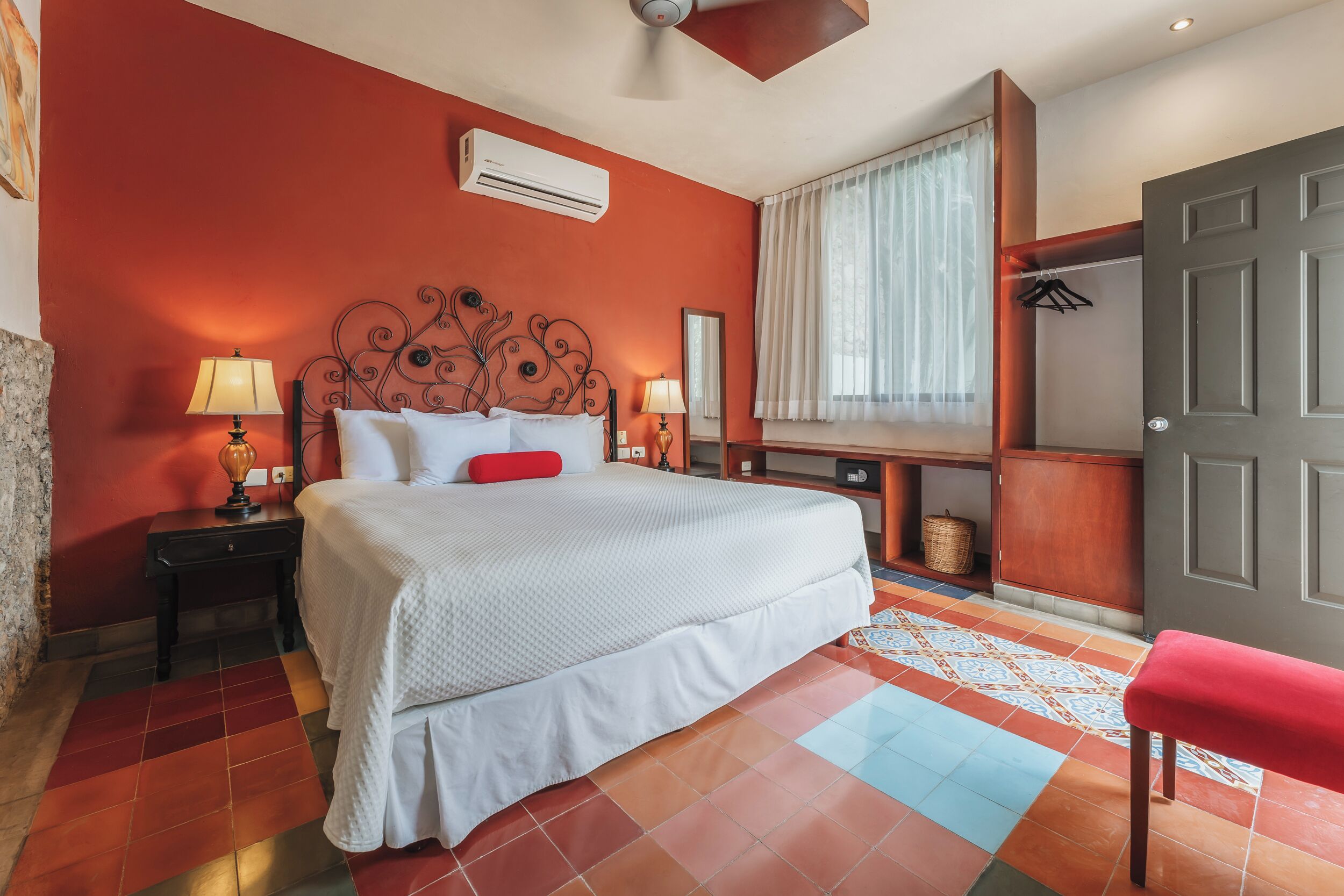 A hotel room with a bed, bedside lamps, a wardrobe, and a window with curtains.