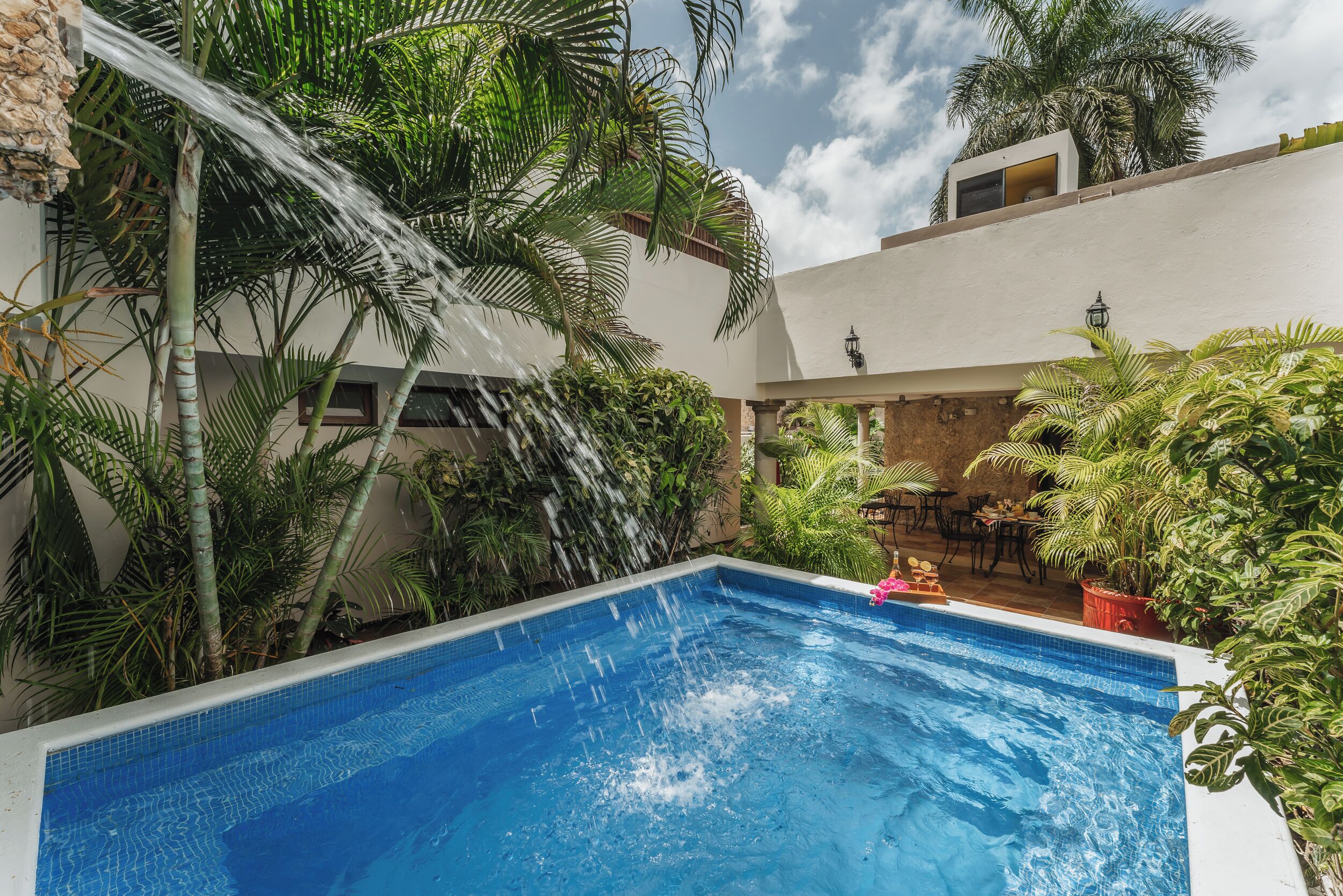 Una piscina con cascada rodeada de exuberante vegetación tropical.