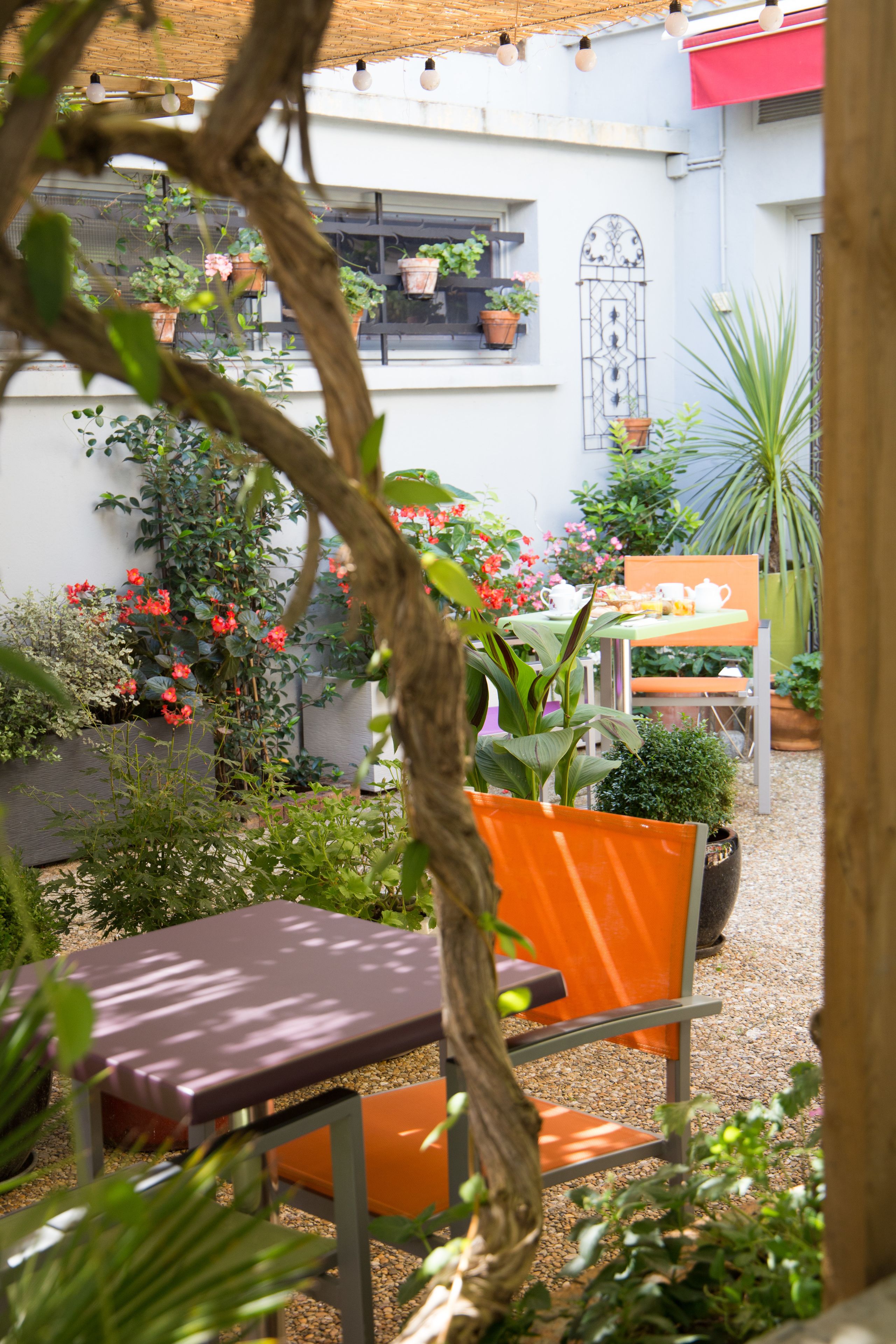 An outdoor seating area with tables and chairs, surrounded by potted plants and flowers.