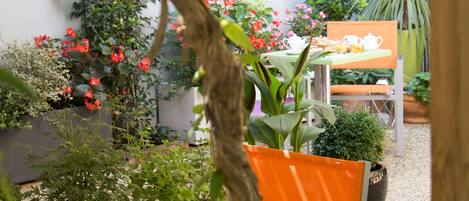 An outdoor seating area with tables and chairs, surrounded by potted plants and flowers.