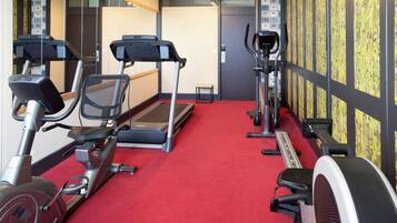 A gym with treadmills, stationary bikes, and a red carpet.
