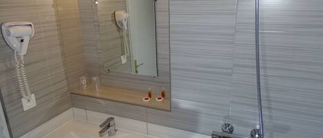 Un baño con lavamanos, espejo, secador de pelo y ducha.