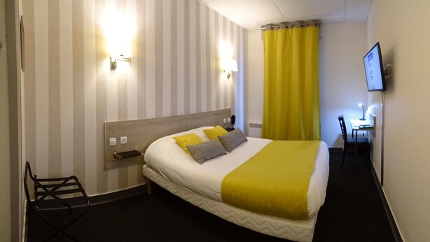 Une chambre d’hôtel avec un lit, un bureau, une chaise et un téléviseur.