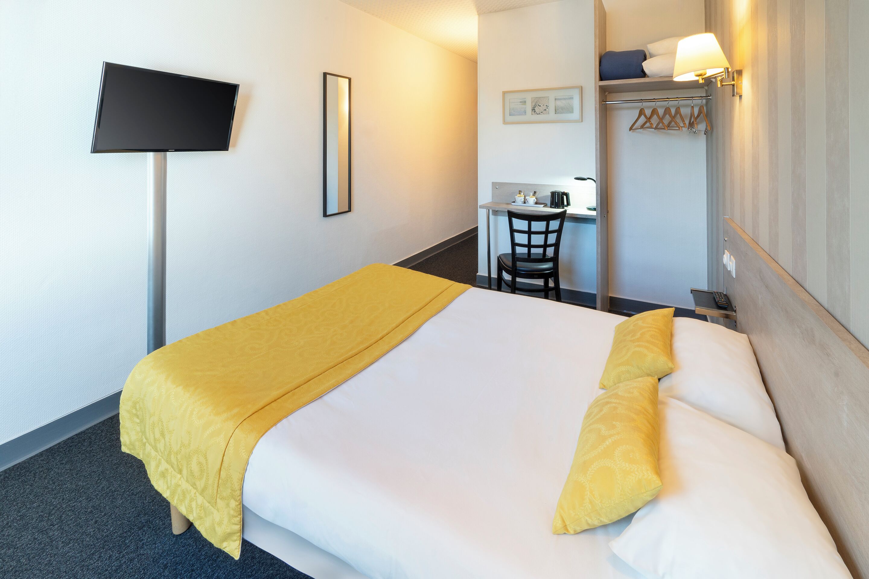 Una habitación de hotel con cama, escritorio y una silla.