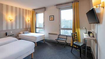 Hotelkamer met twee eenpersoonsbedden, een bureau met stoel, een televisie en een raam met gordijnen.