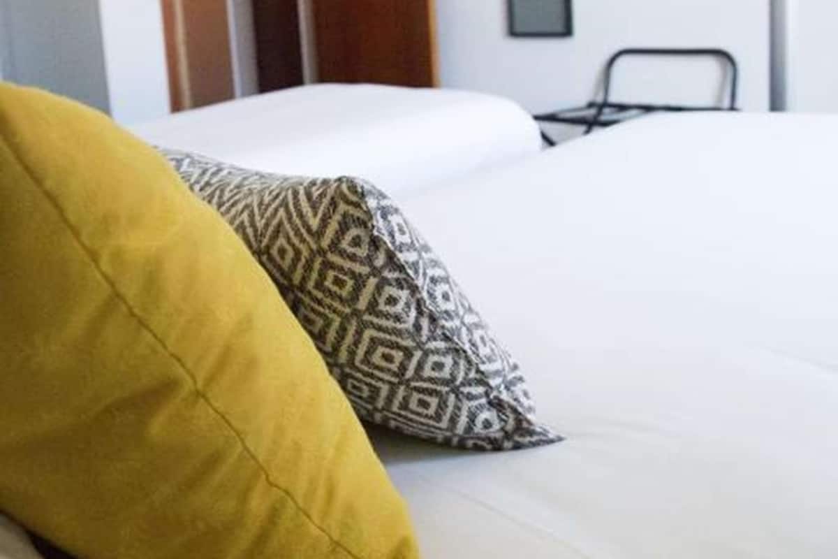 Ein Hotelzimmer mit einem Bett, einem an der Wand befestigten Fernseher und einer Tür zu einem anderen Raum.