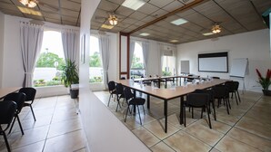 Une salle de conférence équipée d’une longue table, de chaises, d’un tableau blanc et d’un écran de projection.