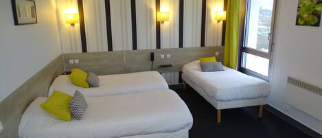 Habitación de hotel con dos camas, cortinas a rayas, luces fijadas a la pared y ventana con vistas.