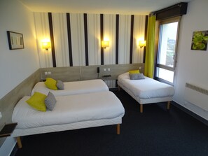 A hotel room with two beds, striped curtains, wall-mounted lights, and a window with a view.