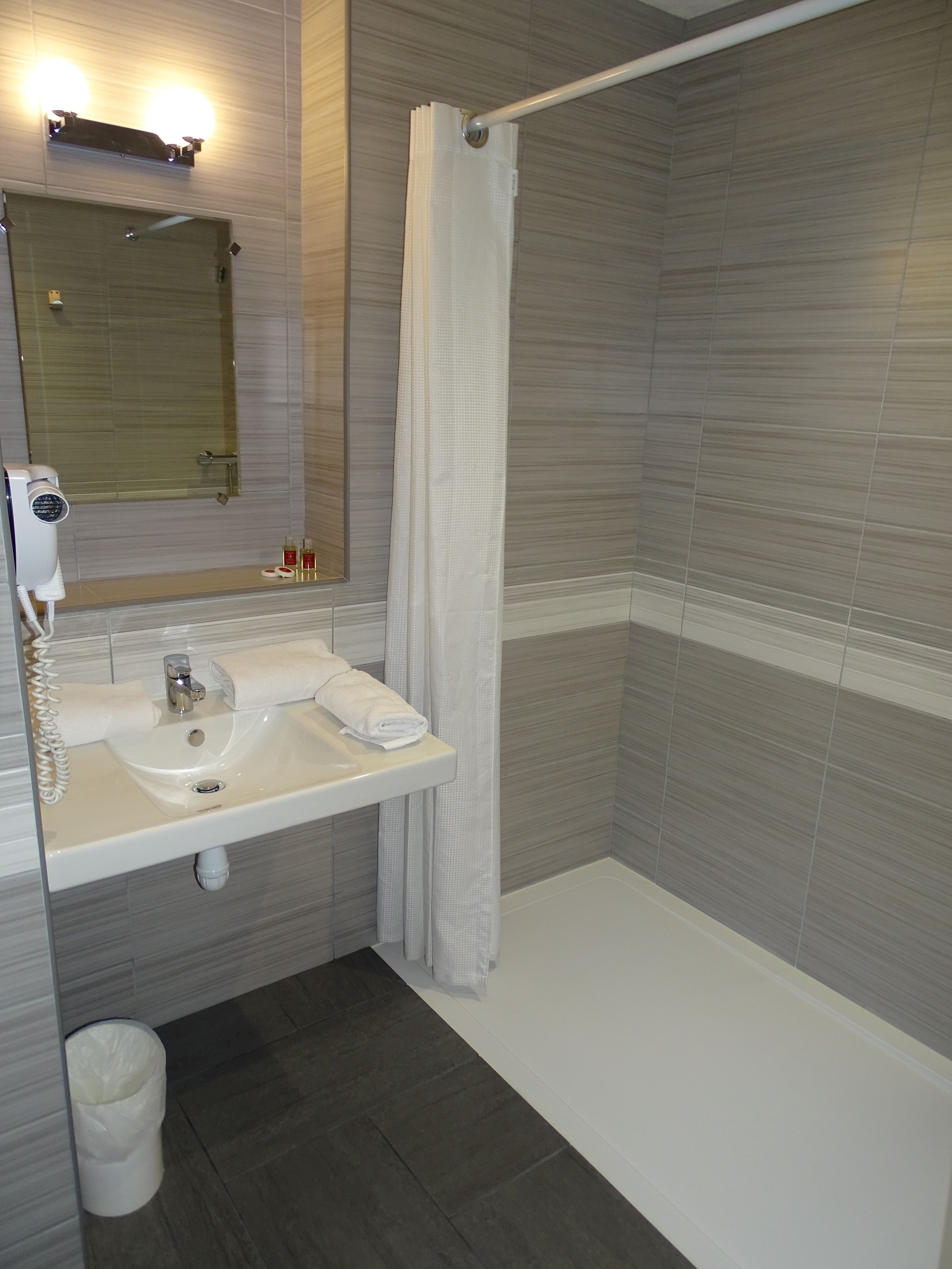 A modern bathroom with a white sink, mirror, and shower curtain.