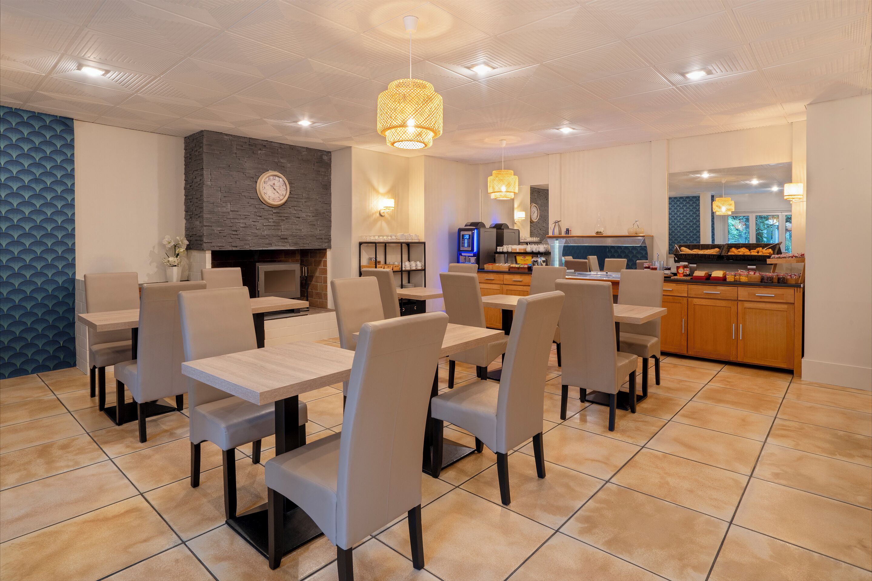 A modern dining area with multiple tables and chairs, a stone accent wall, a fireplace, and a kitchen area in the background.