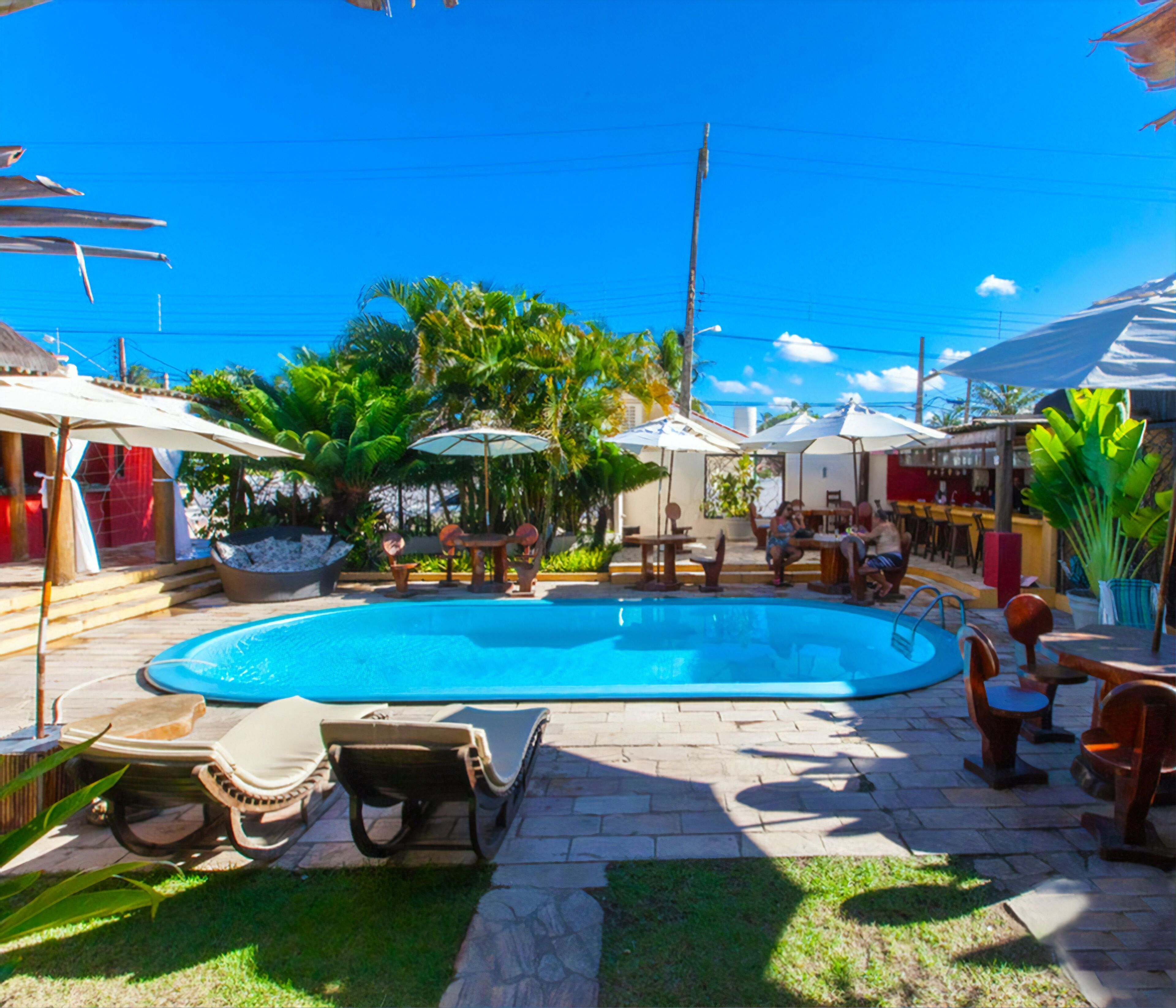 A swimming pool area with lounge chairs, umbrellas, and outdoor seating.