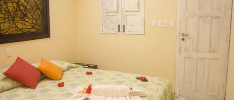Una habitación con una cama, almohadas, una puerta y una obra de arte en la pared.