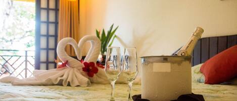 A bed with a bouquet of white swans, two wine glasses, and a champagne bottle in a bucket.