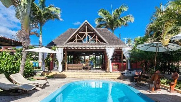 A swimming pool with lounge chairs, a thatched-roof structure, and palm trees. - Hotel Aconchego Porto de Galinhas (Ipojuca)