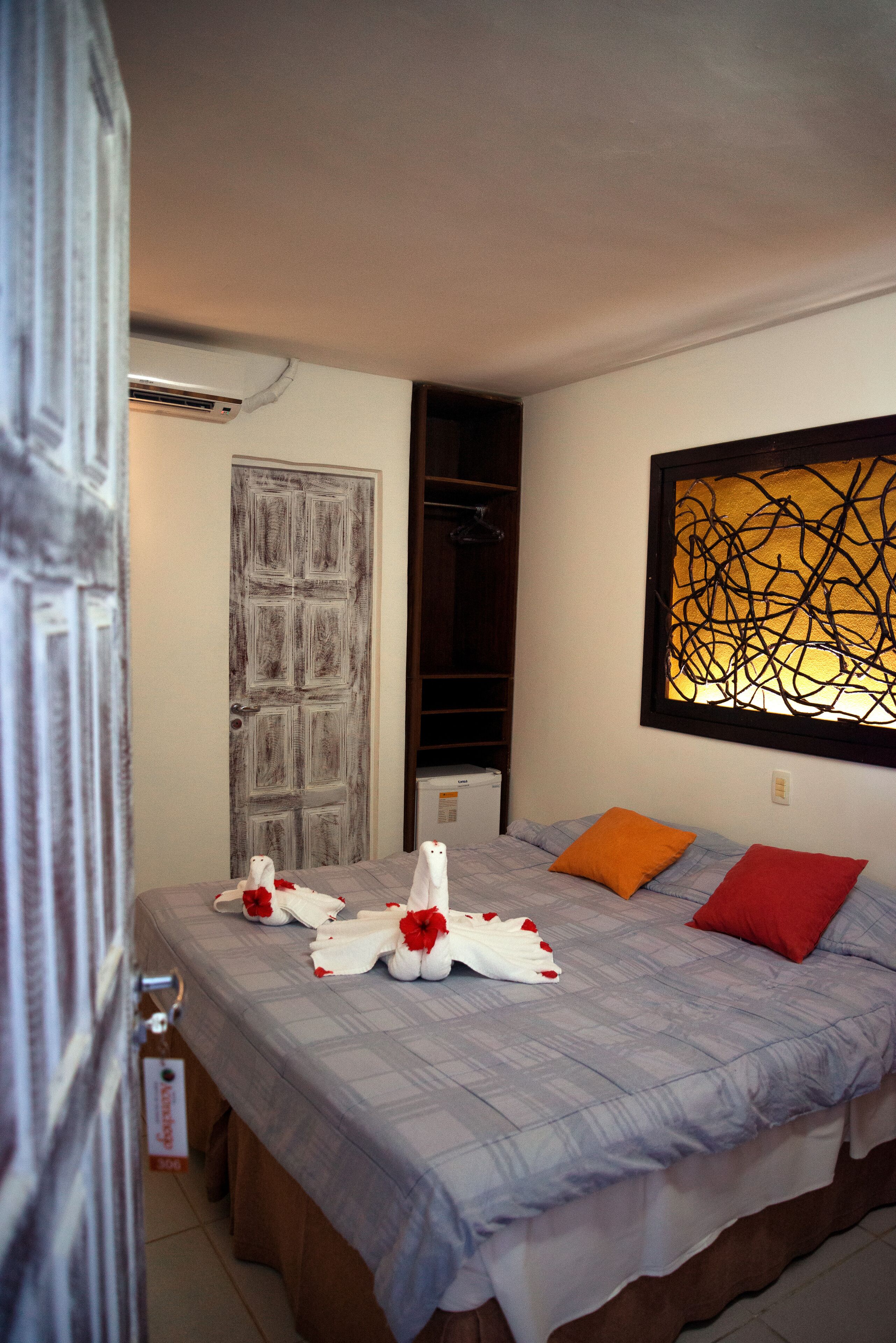 A bedroom with a bed, a door, a wall art piece, and a closet.