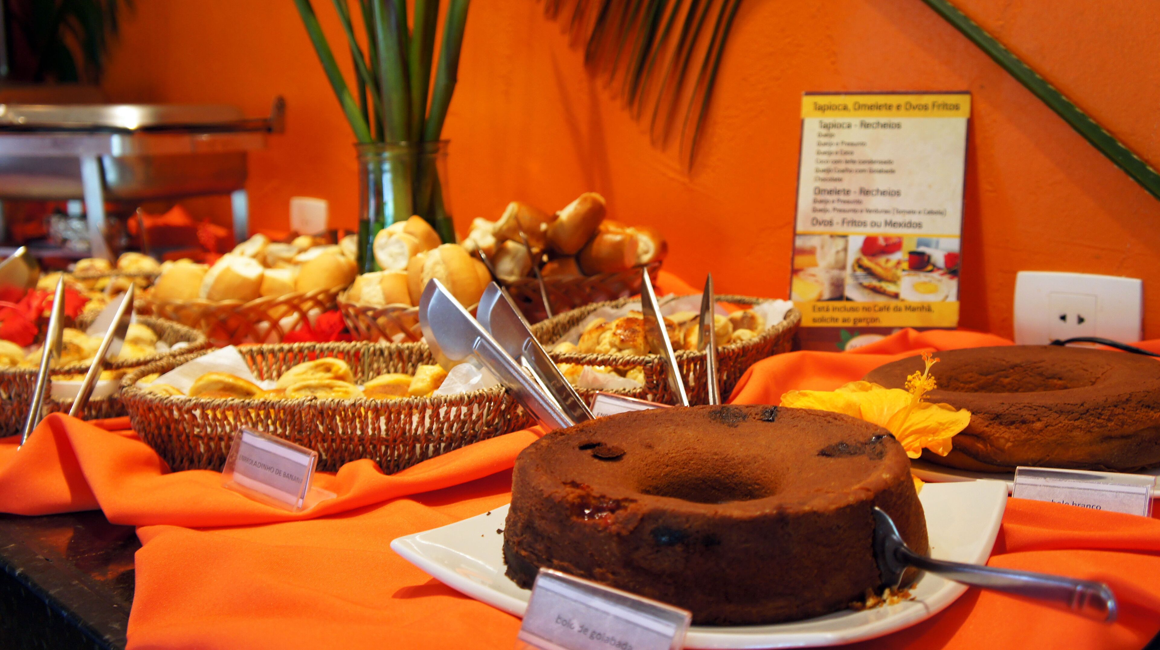 A buffet with various food items including cakes and pastries, with a sign indicating the menu.