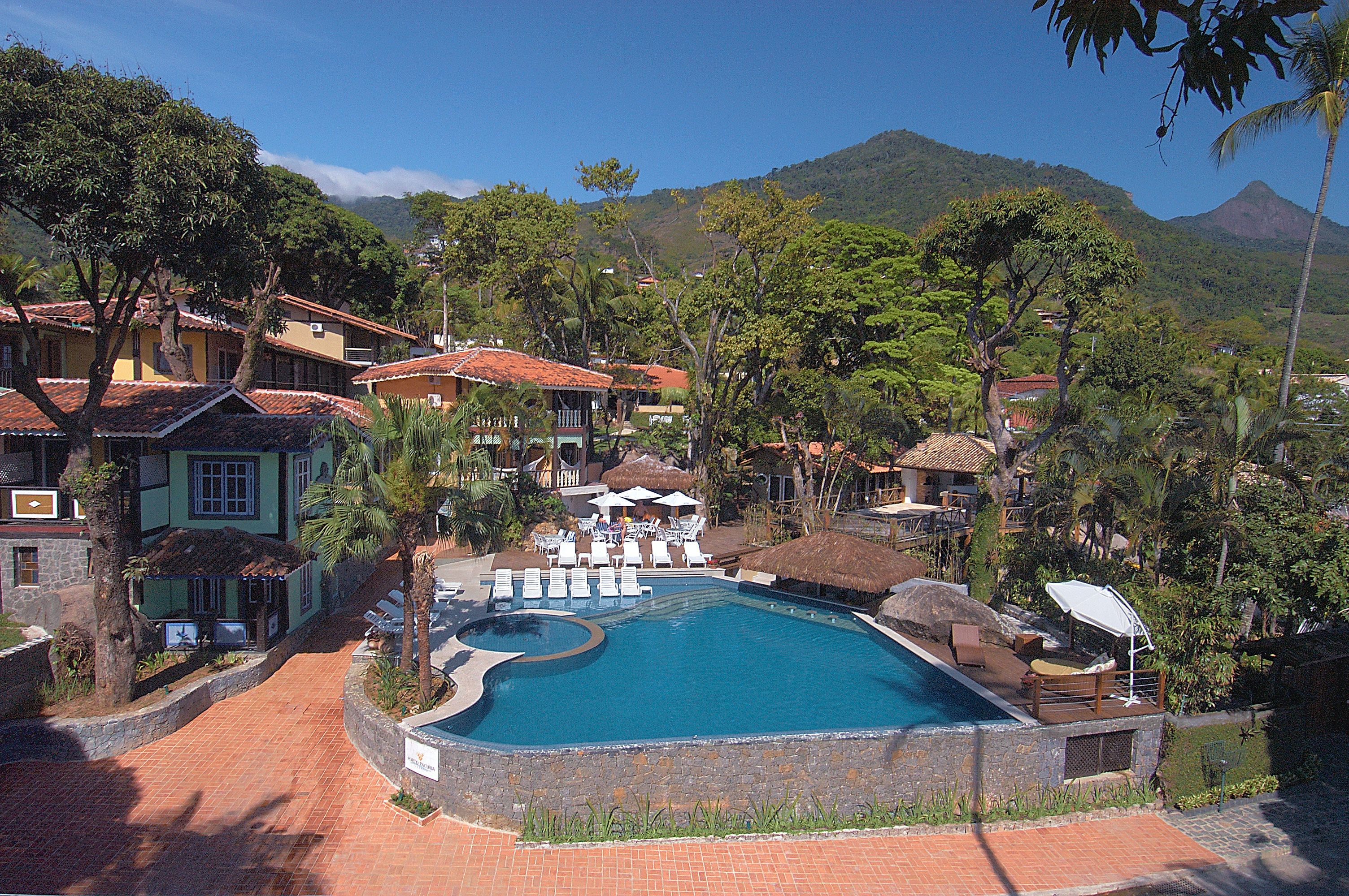 Un complexe hôtelier doté d’une piscine, de chaises longues et d’une végétation tropicale.