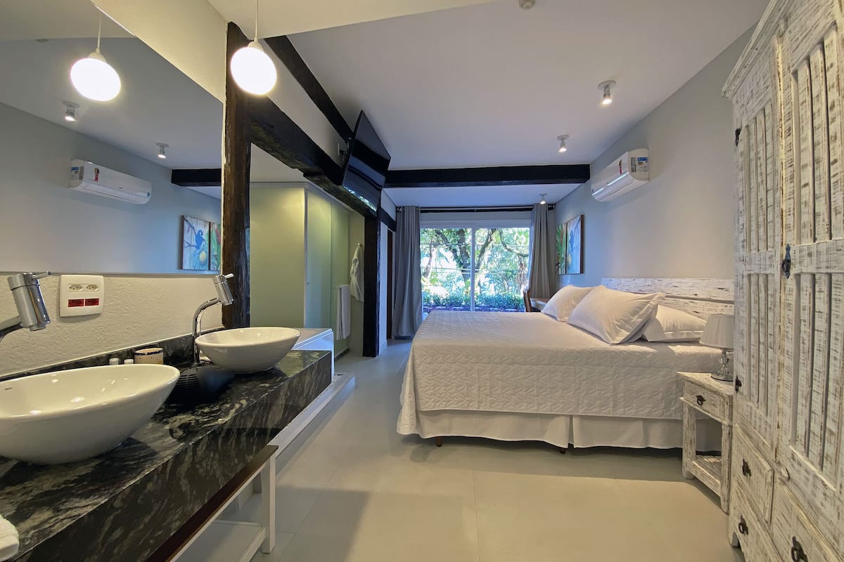 Une chambre moderne avec un grand lit, un lavabo double et une vue sur l’extérieur.