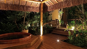 A wooden deck with a hot tub, surrounded by lush greenery and a thatched roof structure. - Porto Pacuiba Hotel Ilhabela (Ilhabela)