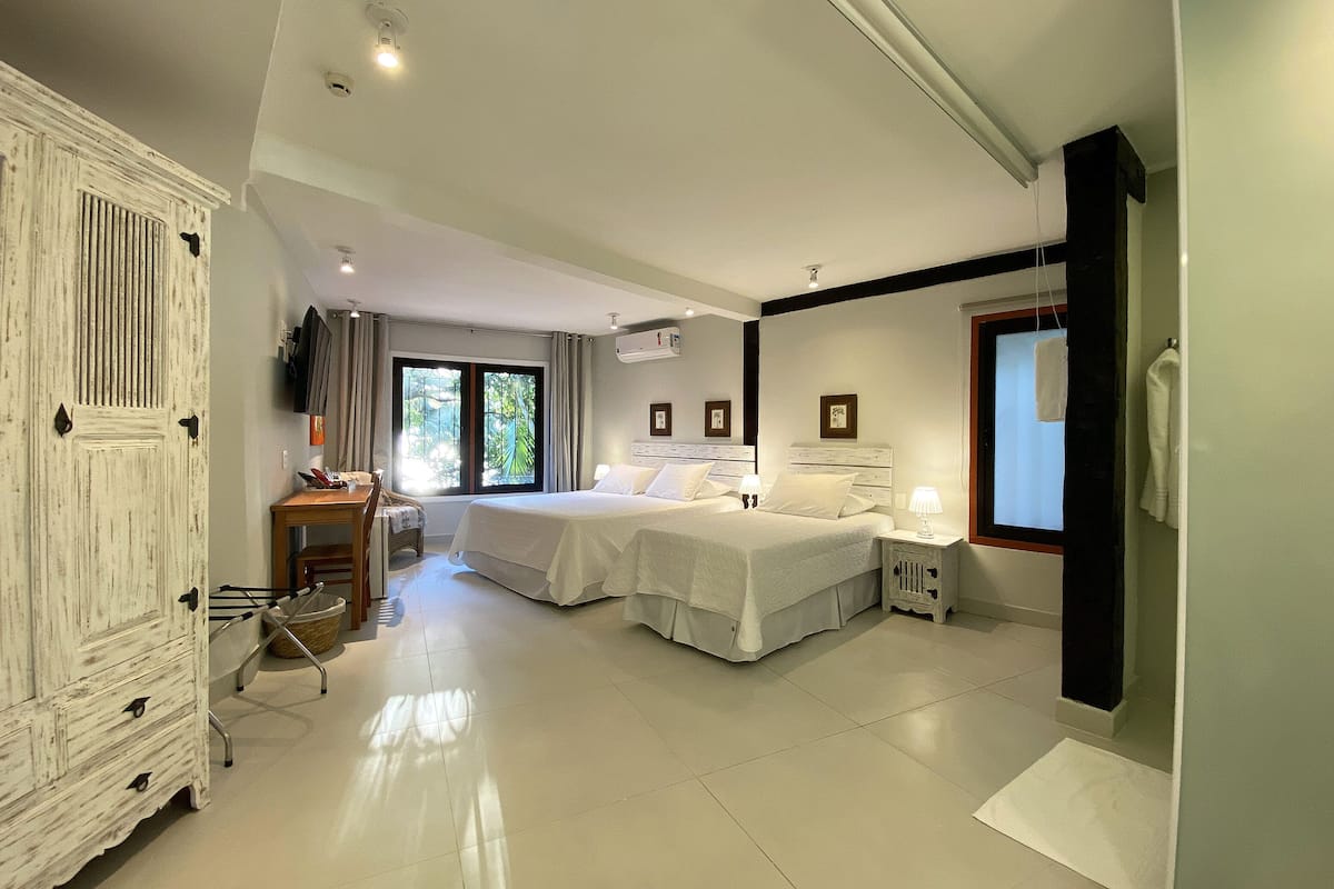 Une chambre d’hôtel spacieuse, équipée de deux lits, d’un bureau et d’une chaise.