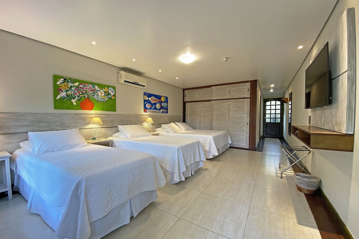 Une chambre d’hôtel avec deux lits, une télévision et des œuvres d’art accrochées au mur.