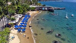 A beach with clear waters, umbrellas, and a pier. - Porto Pacuiba Hotel Ilhabela (Ilhabela)
