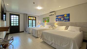 A hotel room with two beds, a TV, a window with curtains, and artwork on the wall.