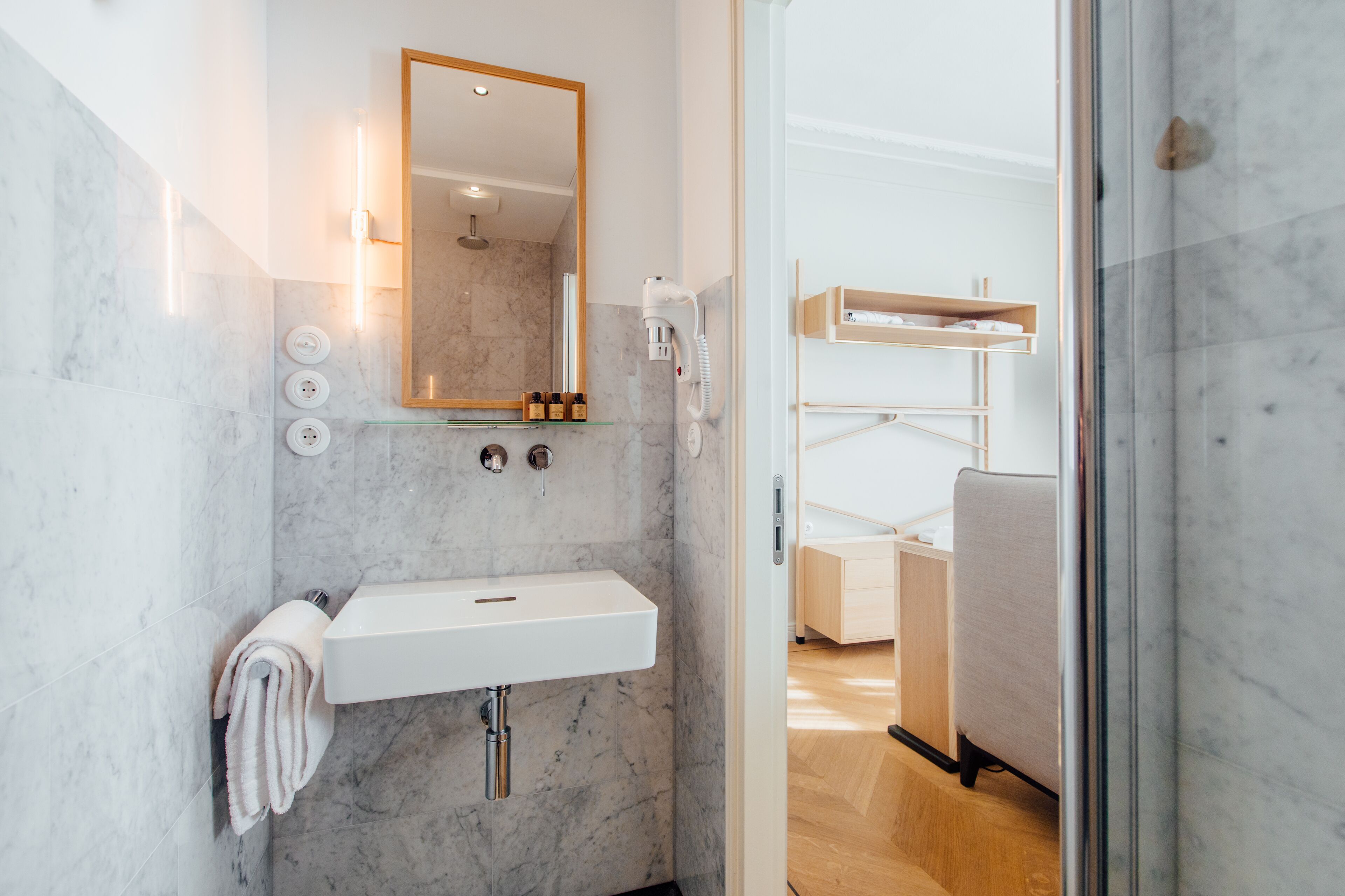 A modern bathroom with a white sink, a mirror, and a glass shower enclosure.
