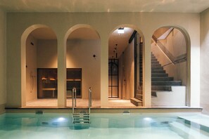A swimming pool with a ladder, arched doorways, and a staircase leading to an upper level. - Maison Haas Hustinx & Spa (Maastricht)