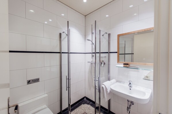 Un baño moderno con cabina de ducha de vidrio, lavamanos blanco y espejo con marco de madera.