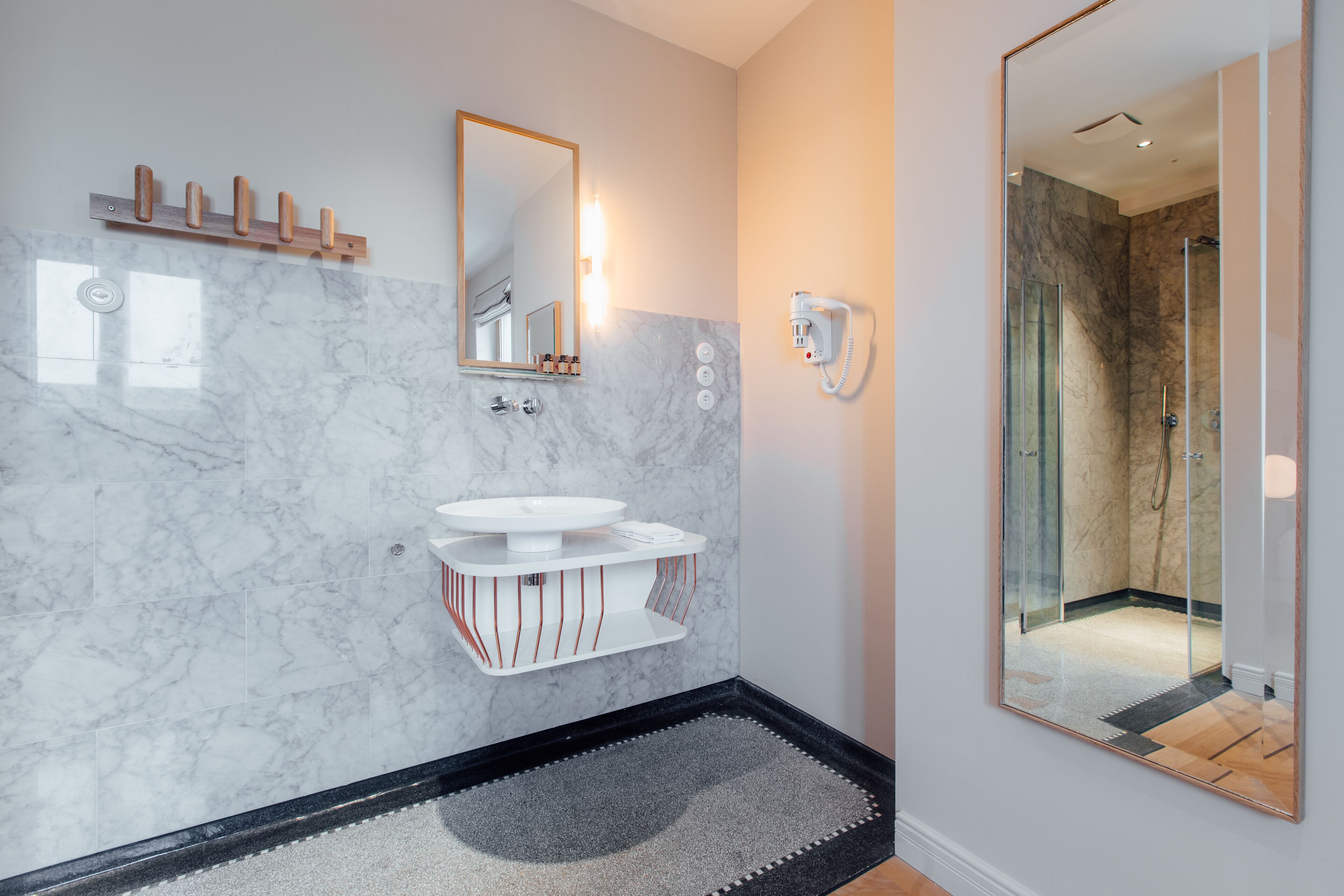 Une salle de bain moderne avec un lavabo en marbre, un grand miroir et une douche à parois de verre.