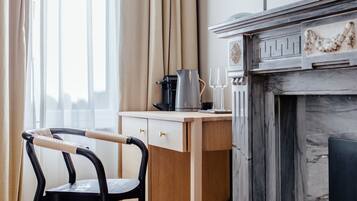 A room with a wooden desk, a chair, a fireplace, and a window with curtains.