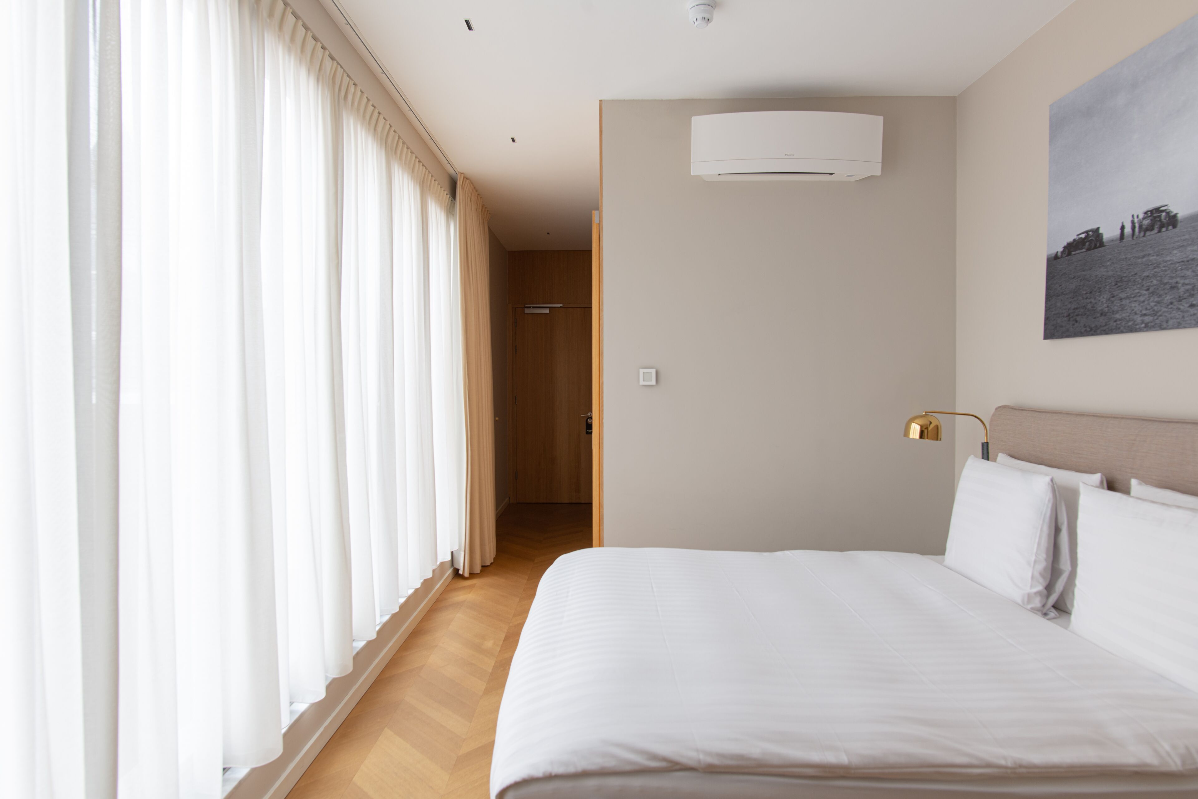 Une chambre d’hôtel avec un grand lit, un tableau au mur et une porte donnant sur une autre pièce.